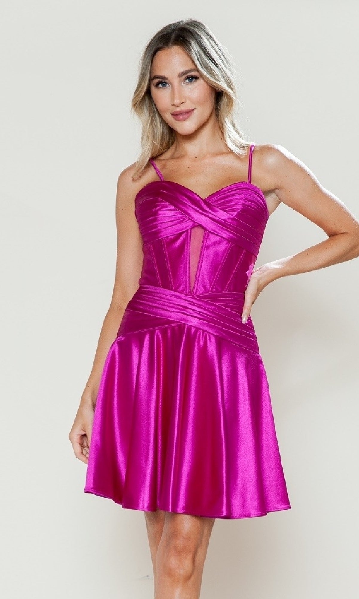 A woman wears the Cut-Out Short Satin Hoco Dress: Poly USA 9632 in bright pink, featuring spaghetti straps, a fitted bodice, and a flared skirt, standing against a plain light background.